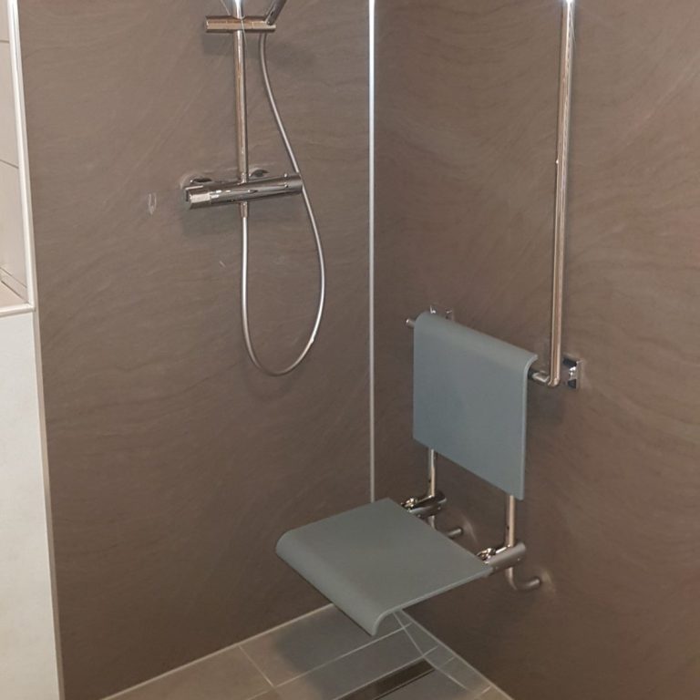 Barrierefreier Duschbereich mit Haltegriffen und klappbarer Sitzgelegenheit.