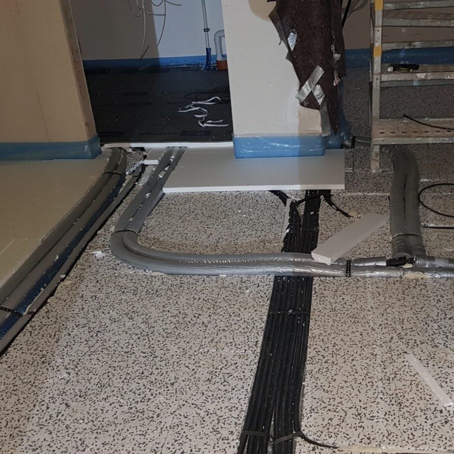 Boden mit Bauarbeiten, sichtbare Kabel und Rohre, blaue Randdämmstreifen.